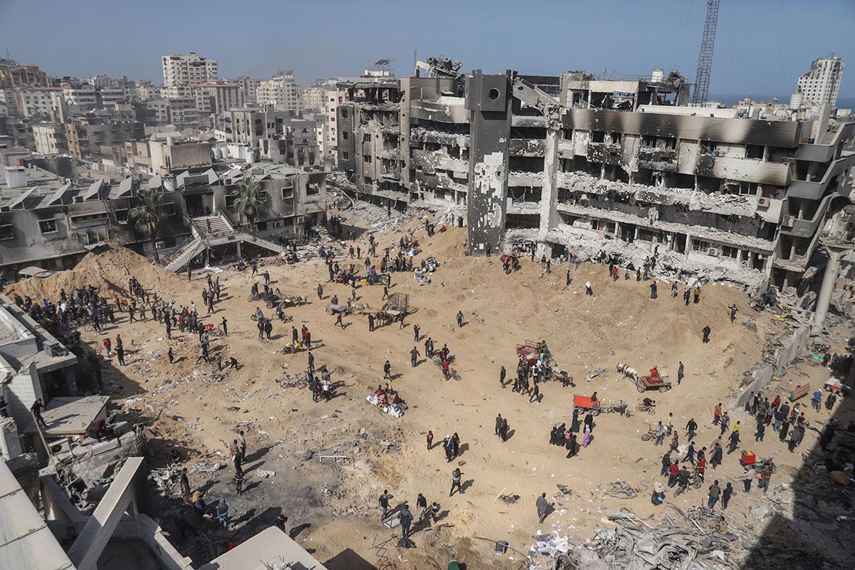 Palestinians walk through the destruction near Shifa Hospital in Gaza City, April 1, 2024