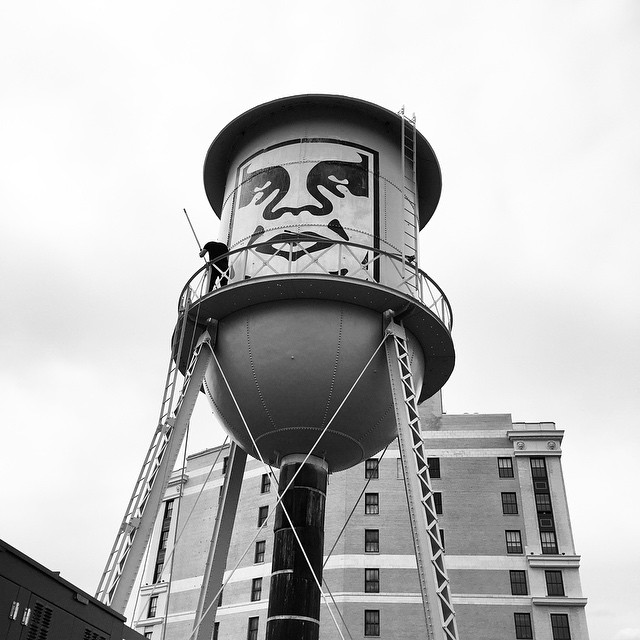 Shepard Fairey pasting up Andre the Giant on a water tower in Detroit.