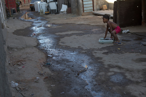 Boy playing next to sewage water slowly running through the Mandela slum in Rio de Janeiro, Brazil, August 2015.