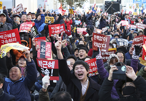 Los manifestantes frente a la Asamblea Nacional, Seúl, Corea, celebran tras escuchar de la audiencia de destitución del presidente Park Geun-hye, 9 de diciembre.