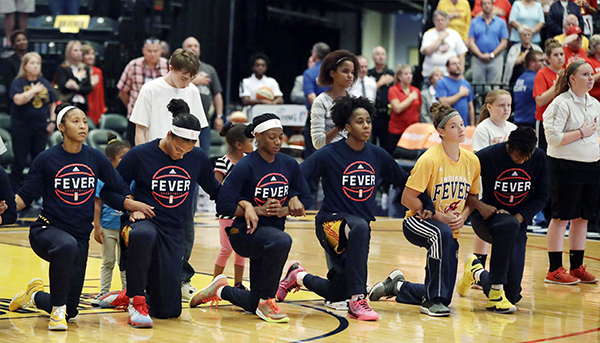 Members of the Indiana Fever kneel during the national anthem