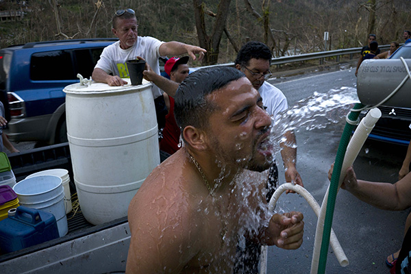 People affected by Hurricane Maria bathe in water piped from a creek in the mountains