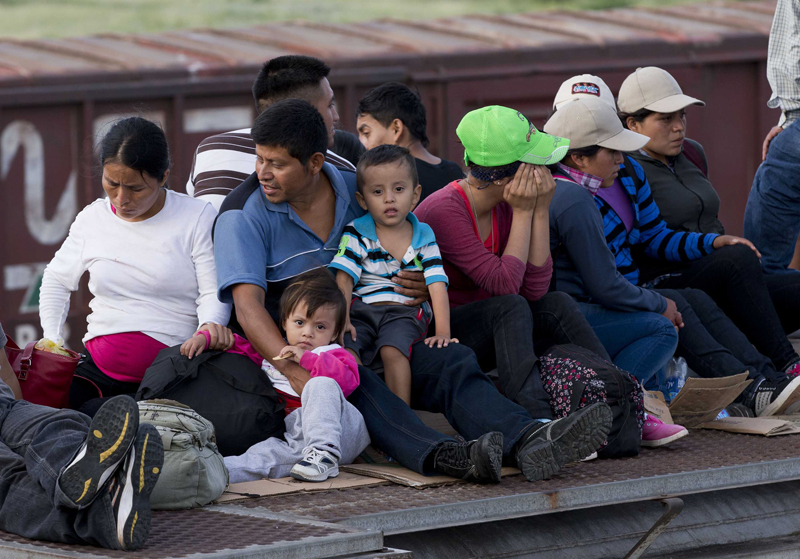 Central American families riding on top of a freight train on the way to the U.S. border