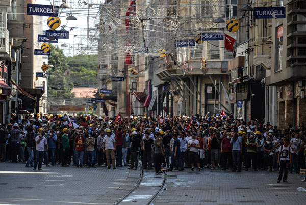 People gather to react as Turkish riot police spray water cannon at demonstrators who remained defiant after authorities evicted activists from an Istanbul park, near the main Taksim Square in Istanbul, Turkey, Sunday, June 16, 2013.