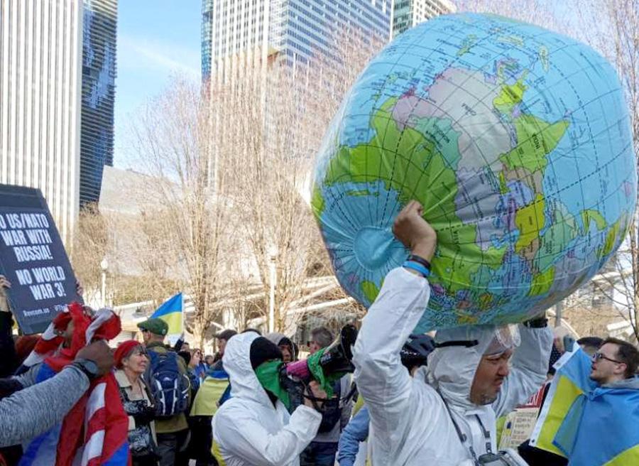 Chicago march against World War 3, April 2, with guy in hazmet suit holding the world.