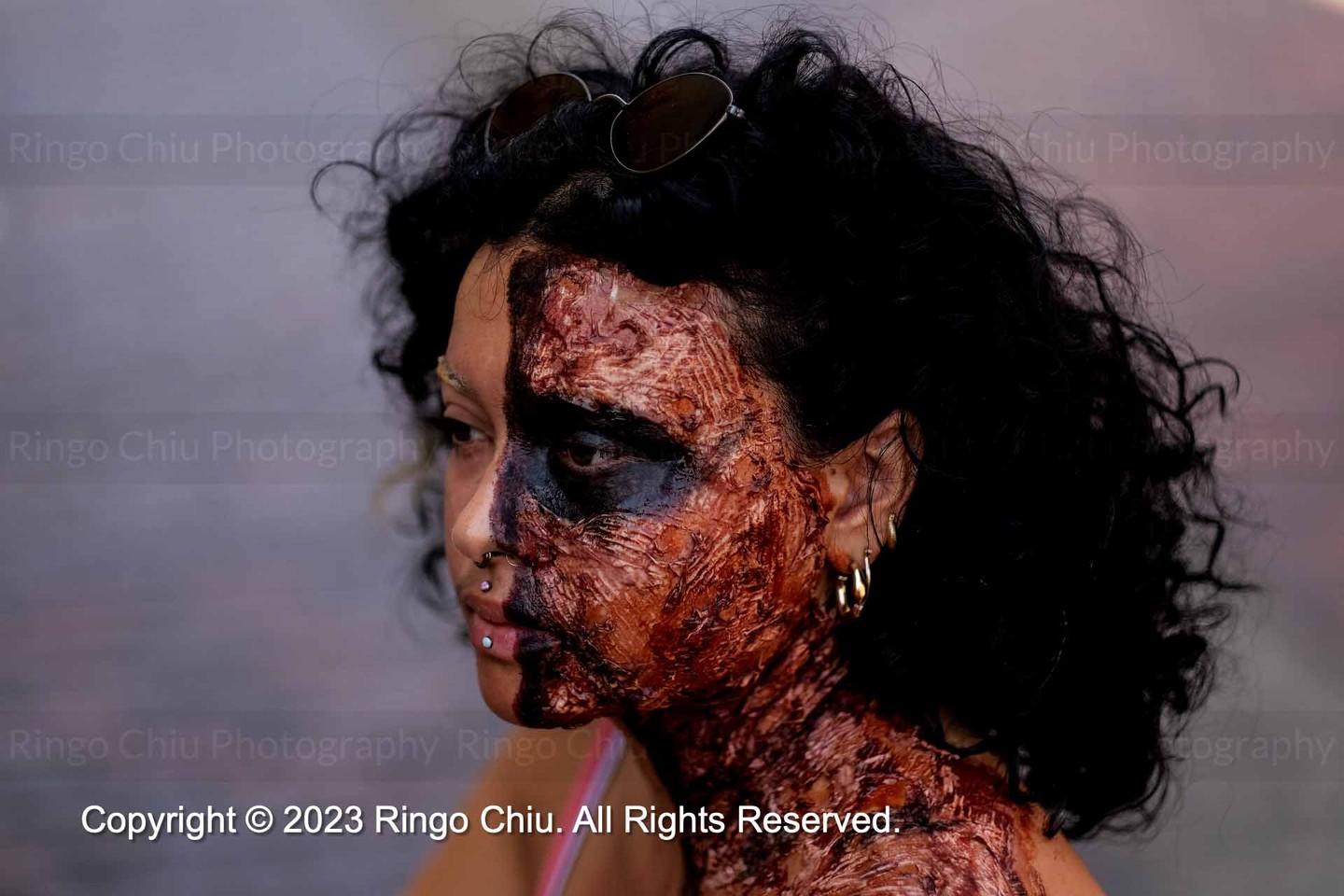 Woman with face disfigured with make up to represent Hiroshima bombing victim.
