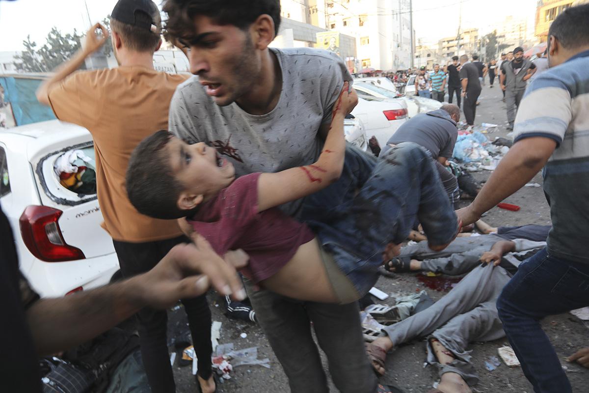 Palestinian carries a boy injured from Israeli airstrike outside the entrance of the al-Shifa hospital in Gaza City, November 3, 2023.