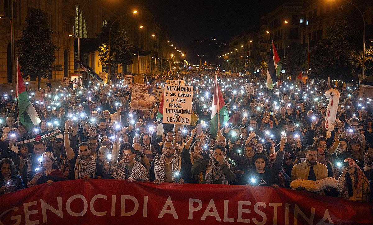 Demonstrators use the flashlights on their mobile phones as they protest against Israeli attacks on Gaza, in Barcelona, Spain, Saturday, Nov. 11, 2023