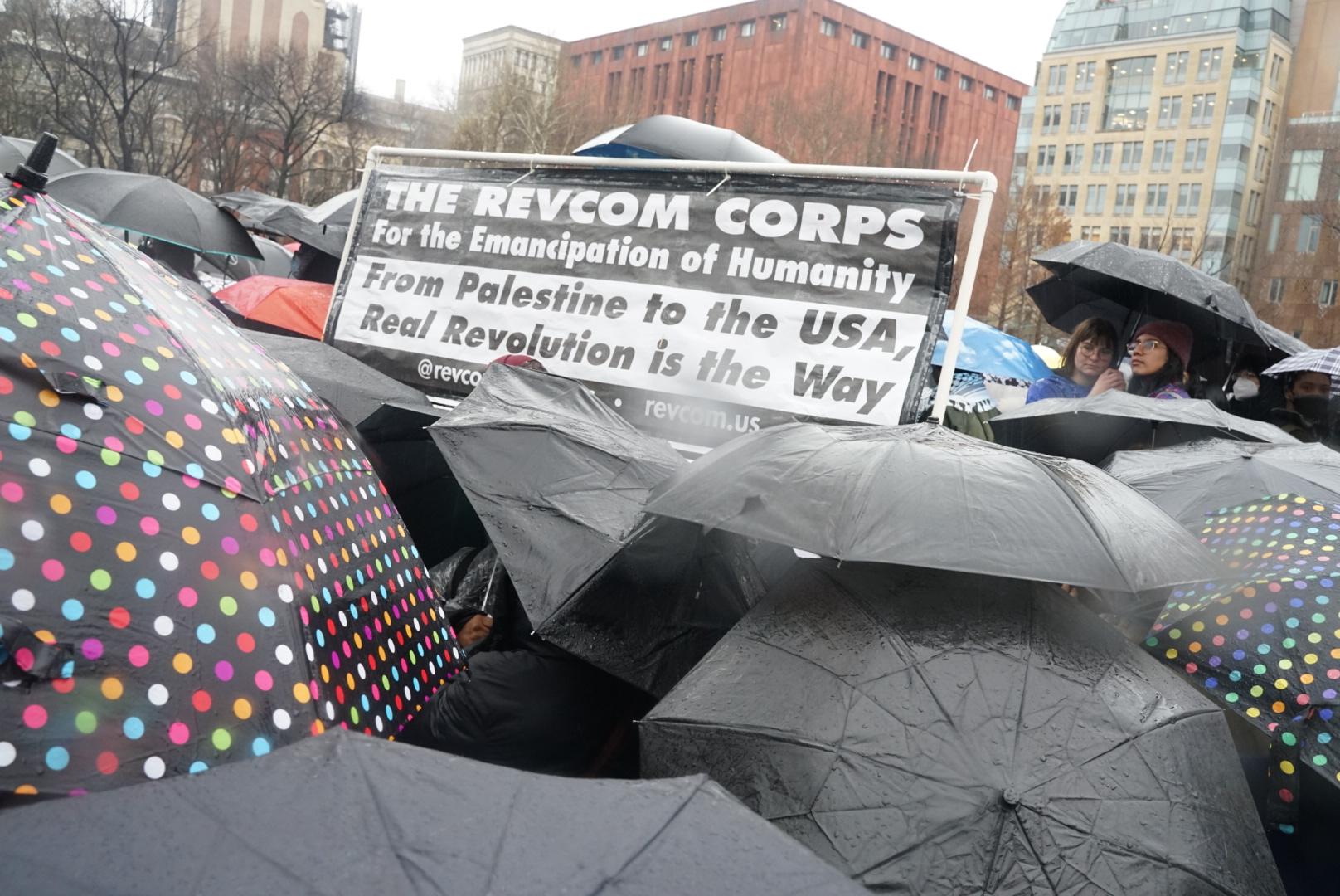 RevCom Corps banner for Palestine above umbrellas at NYC Hands Off Rafah rally, March 2, 2024.