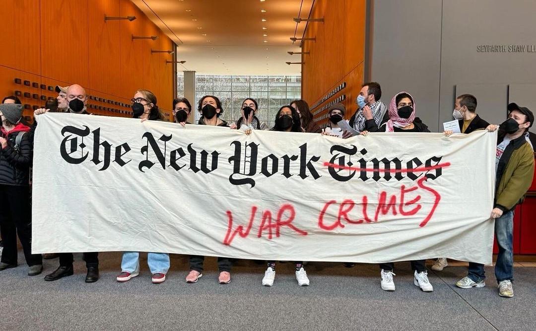 Protest with banner reading The New York War Crimes in the NY Times lobby.