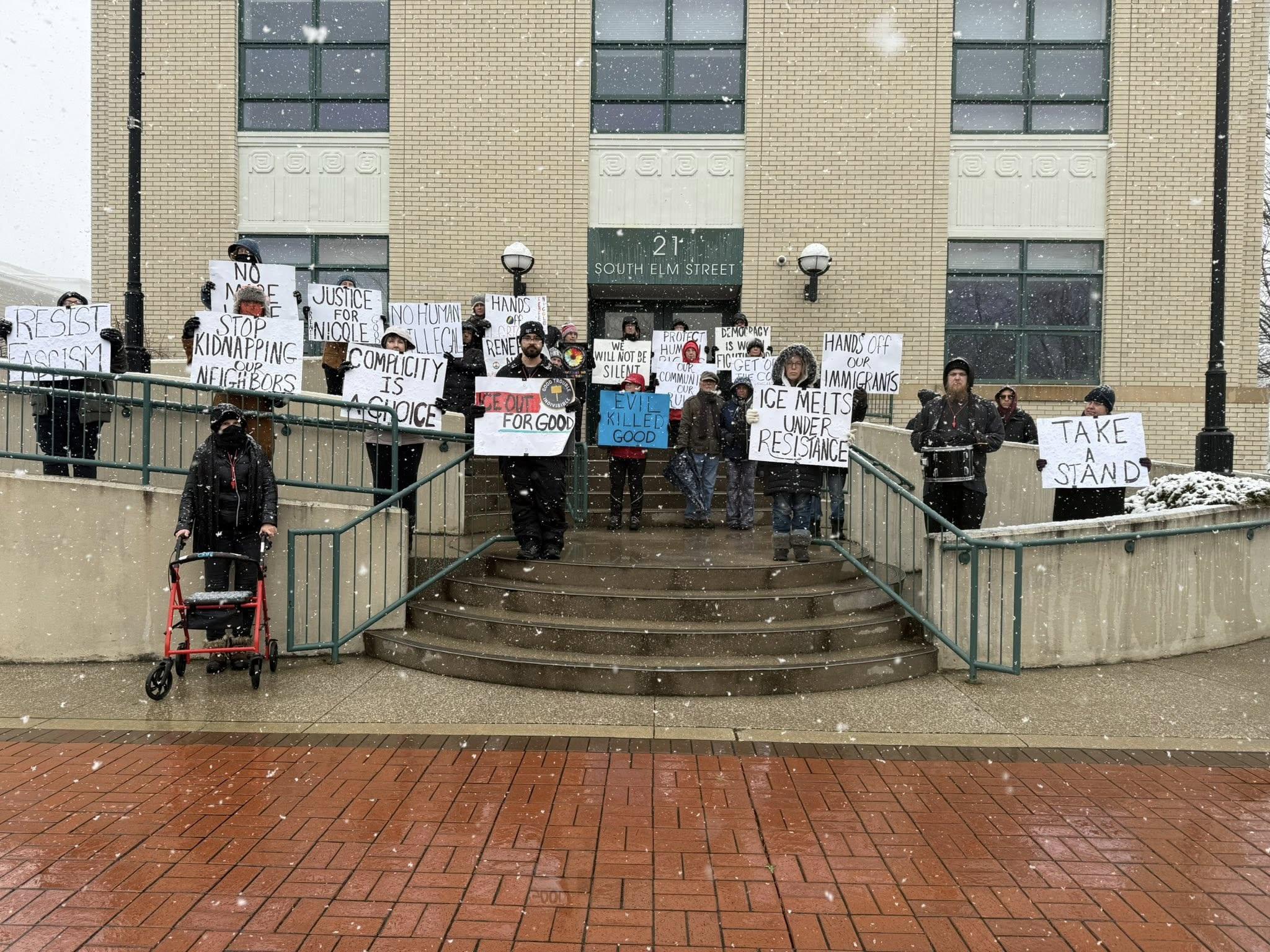 Group holding anti-ICE signs in cold rain in Saugatuck, Michigan.