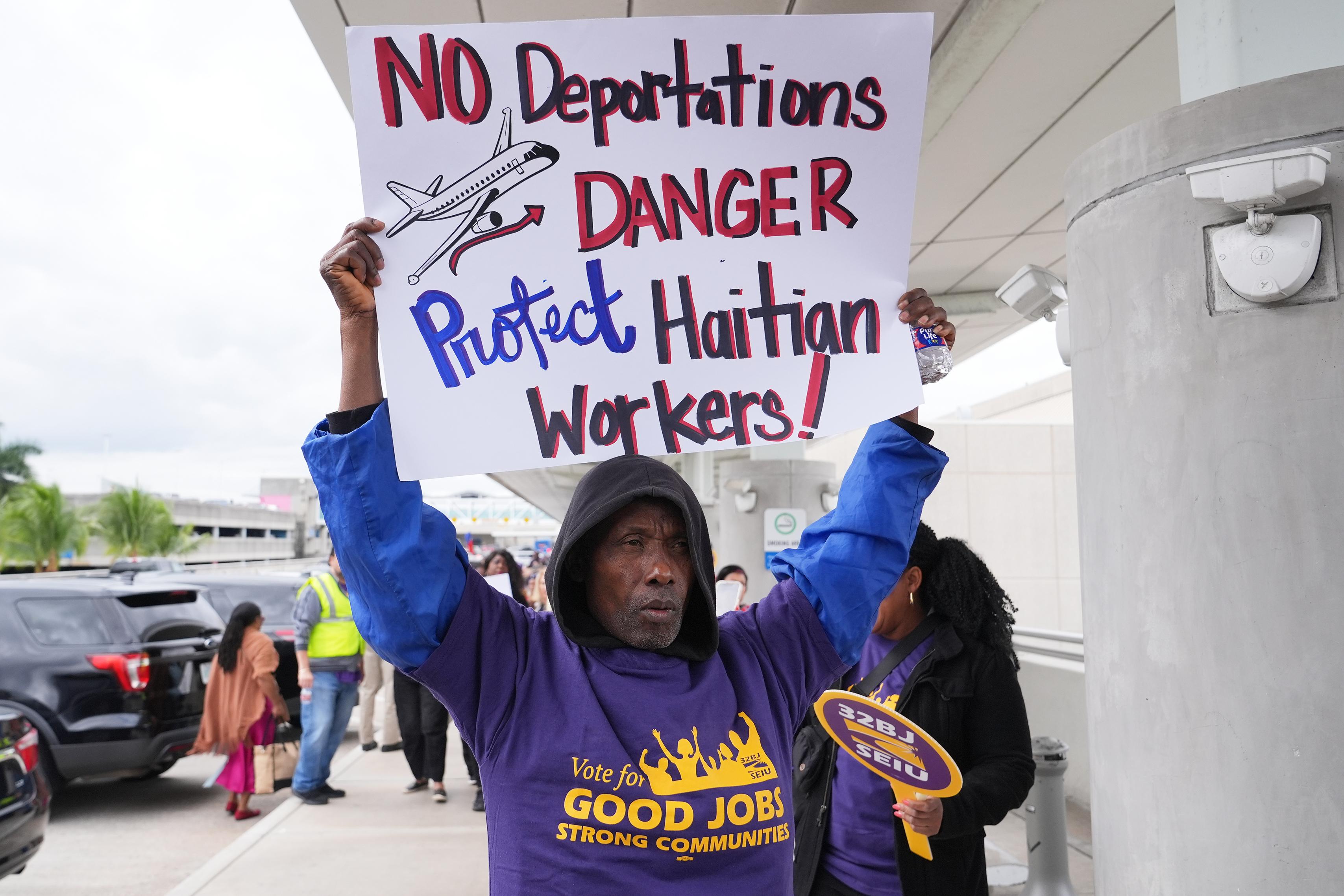 Man holds a sign At a rally for Temporary Protected Status (TPS) for Haitian immigrants in Fort Lauderdale, Florida, January 2026.