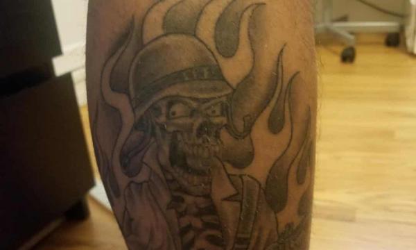 Tattoo on calf of LA sheriffs of skull with Nazi-style helmet and rifle encircled by flames