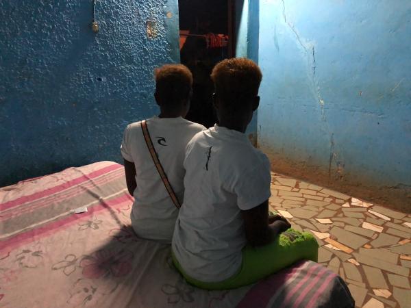 Nigerian women trafficked to Burkina Faso sit close together on a bed