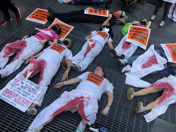 Pro abortion protesters wearing bloody pants do a die-in in Times Square, NYC.