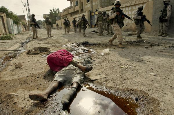 U.S. soldiers run past dead body in the street of Fallujah.