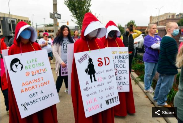 Three women dressed as handmaids protest October 2 in Minnehaha South Dakota