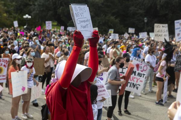 People, including woman in handmaid's red dress, protest anti-abortion law in Austin, Texas.