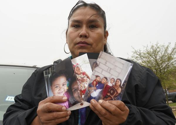 Woman holds photos of three daughters separated from her in Texas.