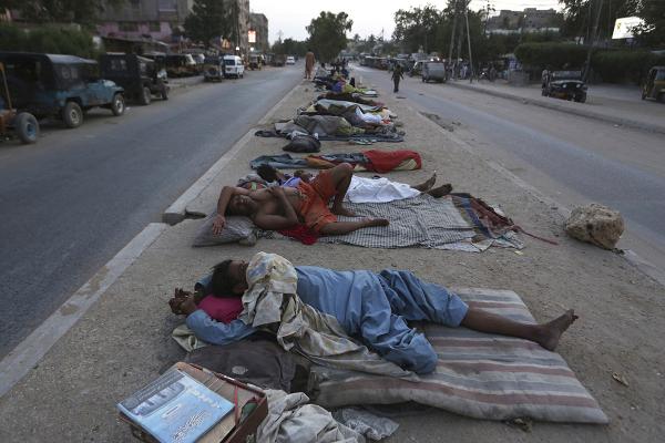Because of relentless heat, Pakistani laborers sleep in the street.