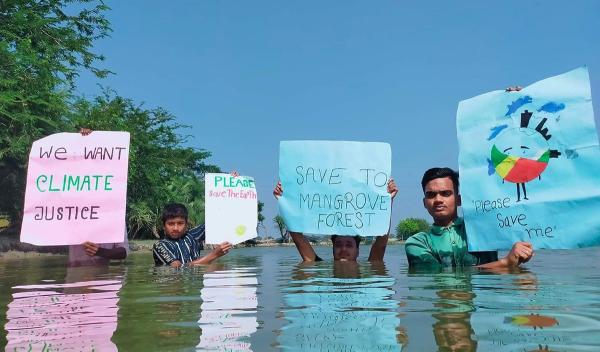 Bangladesh protesters chest deep in water holding up signs, November 5, 2021