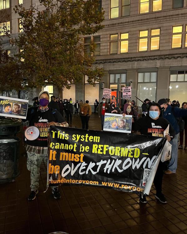 RevClub with banner—"Rittenhouse and Whole System Guilty" at protest in Oakland 