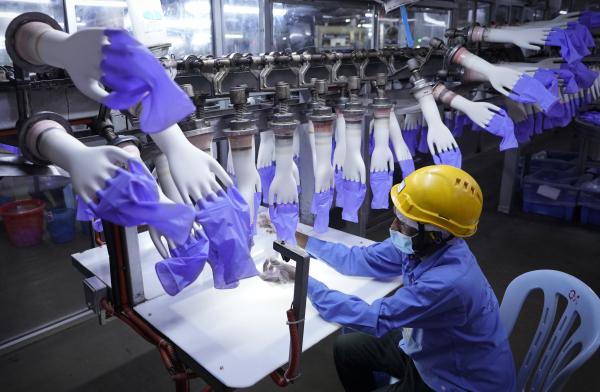 Workers produce protective rubber gloves in Malaysian factory, which are shipped to rich countries.