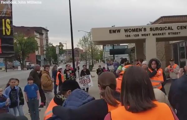 Abortion escorts lead woman through crowd of harrassing antiabortionists.