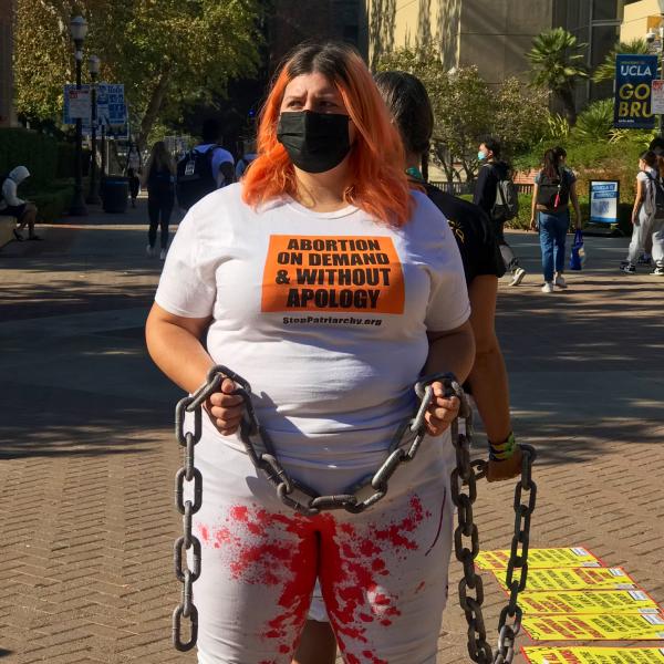 Woman in chains, bloody pants, protests attacks on right to abortion.