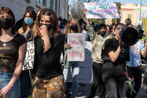 Woman on bullhorn leads chants at International Women's Day march in Berkeley.