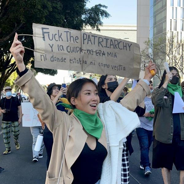 Woman with sign "Fuck the Patriarchy" and slogan in Spanish.