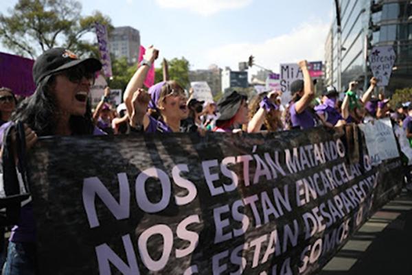 Women with banner protest attacks on abortion in Mexico.
