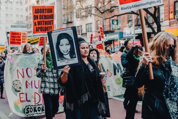 Young women march with Abortion On Demand Without Apology signs in New York City for International Women's Day.