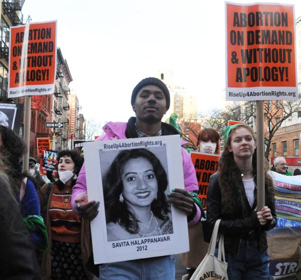 Man with picture of victim of botched abortion in IWD march in New York City.