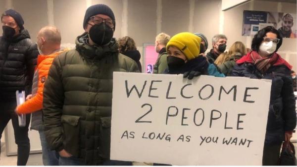 Europeans hold welcome signs to greet Ukrainian refugees.