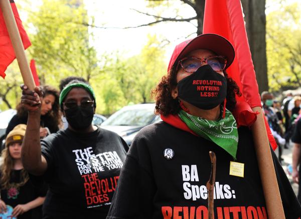 Women carrying red flags listen to speakers at New York City May Day rally.