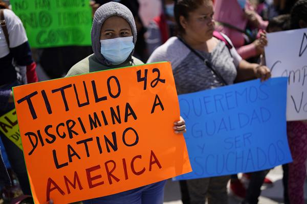 A woman holds a sign that reads "Title 42 discriminates against Latin America," during a protest of people waiting in Mexico as they hope to apply for asylum, 
