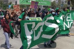 Young woman marching behind green banner