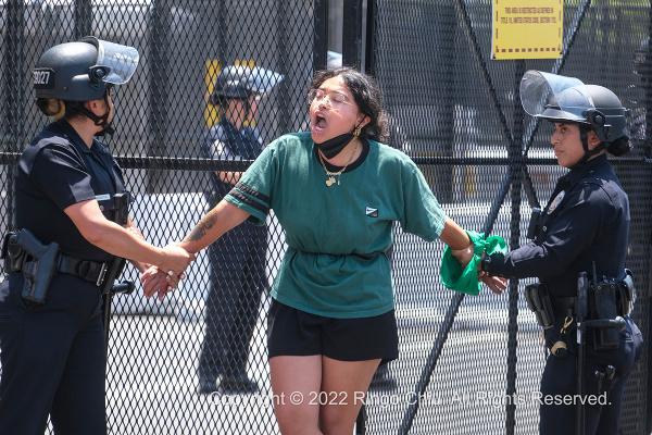 RU4AR activist chains herself to fence at Summit of the Americas conference in LA, June 9, 2022.