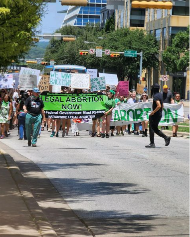 RU4AR march in Austin TX with green banner "Legal Abortion Now!"