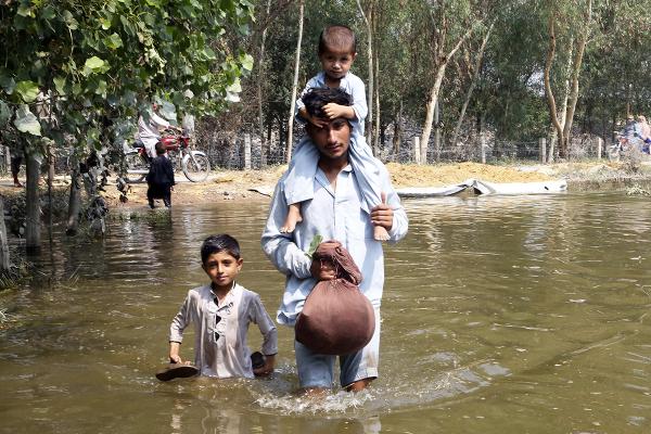 Pakistan father with two children stand in flood waters