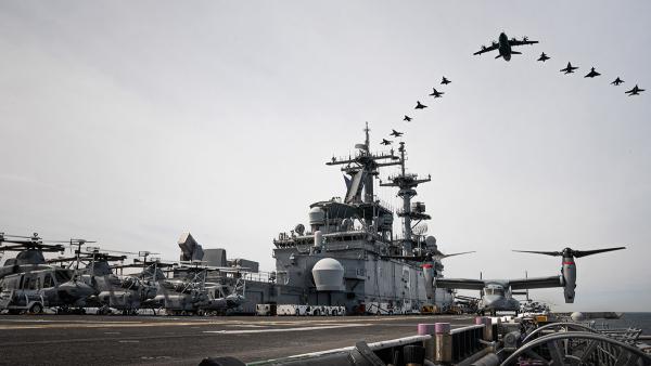 Aircraft from Germany, Finland, Sweden, and the United States fly in formation above the Wasp-class amphibious assault ship USS Kearsarge.