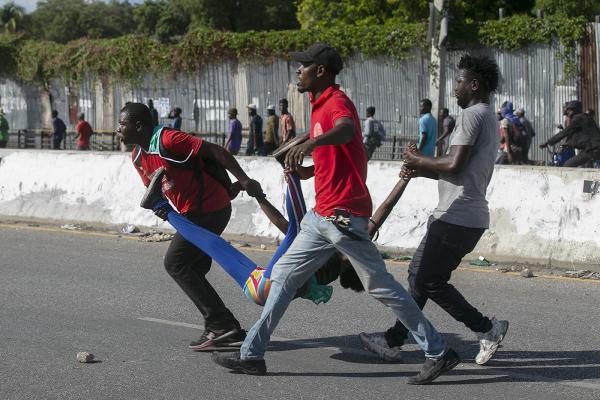 Haitian protesters carry a woman wounded in police fire, October 10, 2022.