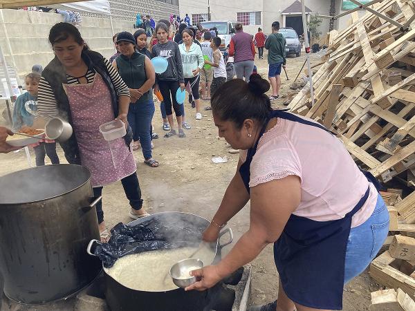 Woman serves rice and beans to Venezuelan migrants at Tijuana's largest migrant shelter.