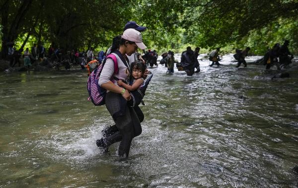 Immigrants wade over one of many rivers while crossing treacherous Darién Gap. 