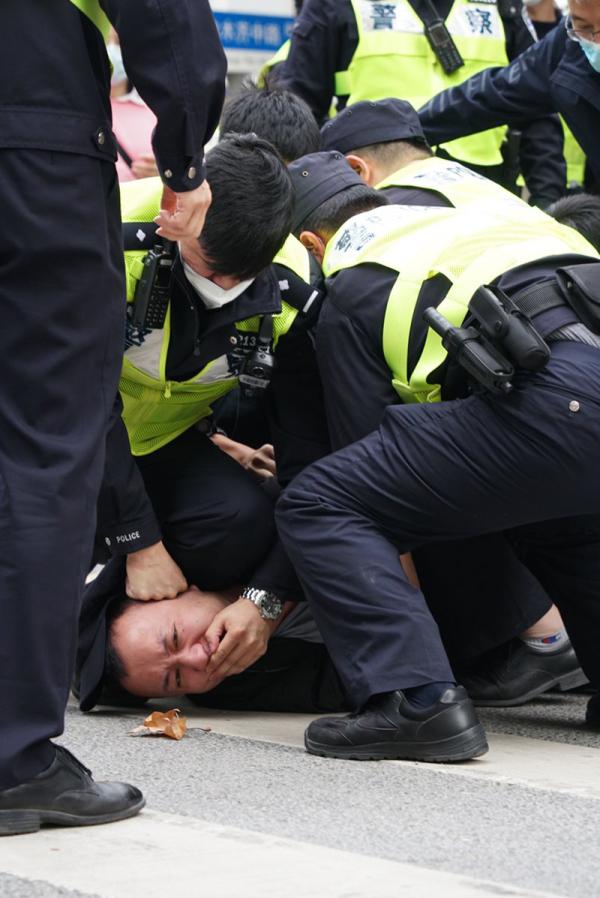 Shanghai cops kneel on protester and cover his mouth.