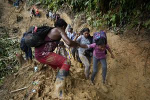 Venezuelan migrants wade through mud to cross the Darién Gap.