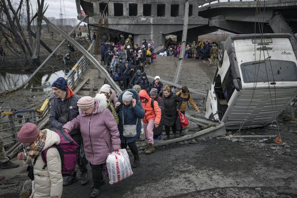 March 5, 2022, Ukraine: People cross path under a bridge destroyed by Russian airstrike.