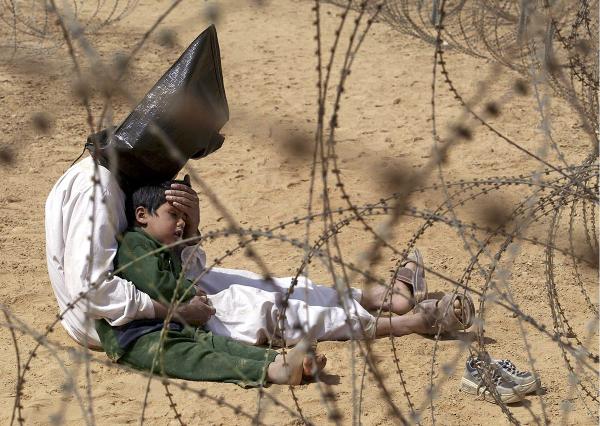 Iraqi prisoner of war, seen behind barbed wire fence, comforts his 4-year-old son.