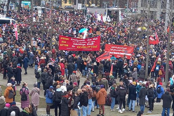 Berlin, IWD 2023, revolutionary banners held high in crowd